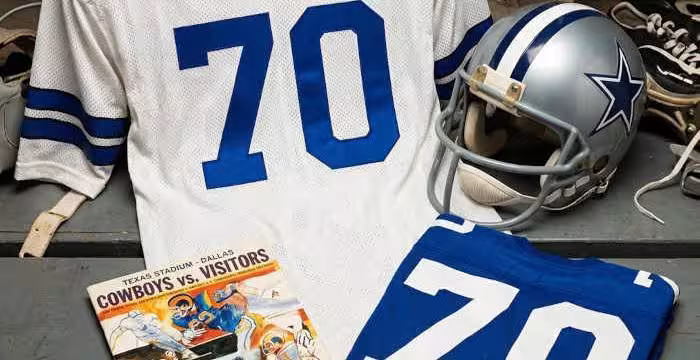 Gemini AI created image of a 1973-era Dallas NFL American football jersey 70, without a name on it, and a matching period-correct helmet, the program cover appropriate to the era and team.