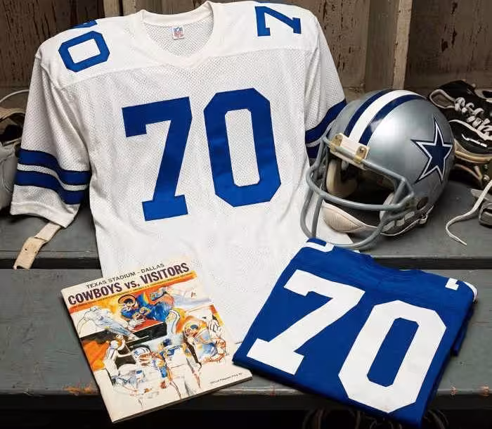 Gemini AI created image of a 1973-era Dallas NFL American football jersey 70, without a name on it, and a matching period-correct helmet, the program cover appropriate to the era and team.