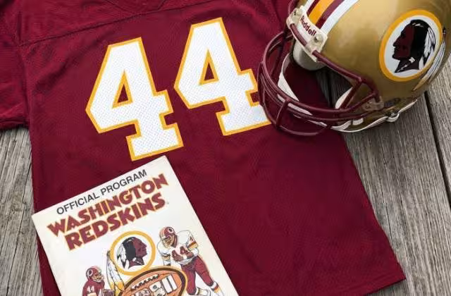 Gemini AI generated image of a 1980s-era red American football jersey 44, without a name on it, and a matching period-correct helmet, the program cover appropriate to the era and team.