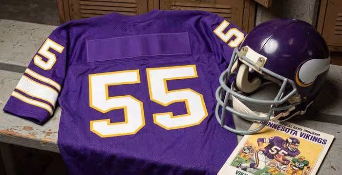 Gemini AI-created image of a 1982-era Minnesota NFL American football jersey 55, without a name on it, and a matching period-correct helmet, the program cover appropriate to the era and team.