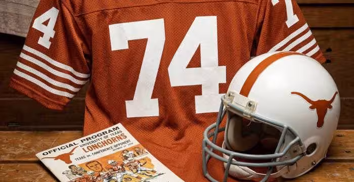 Gemini AI-created image of a 1970-era Texas American football jersey 74, without a name on it, and a matching period-correct helmet, the program cover appropriate to the era and team.