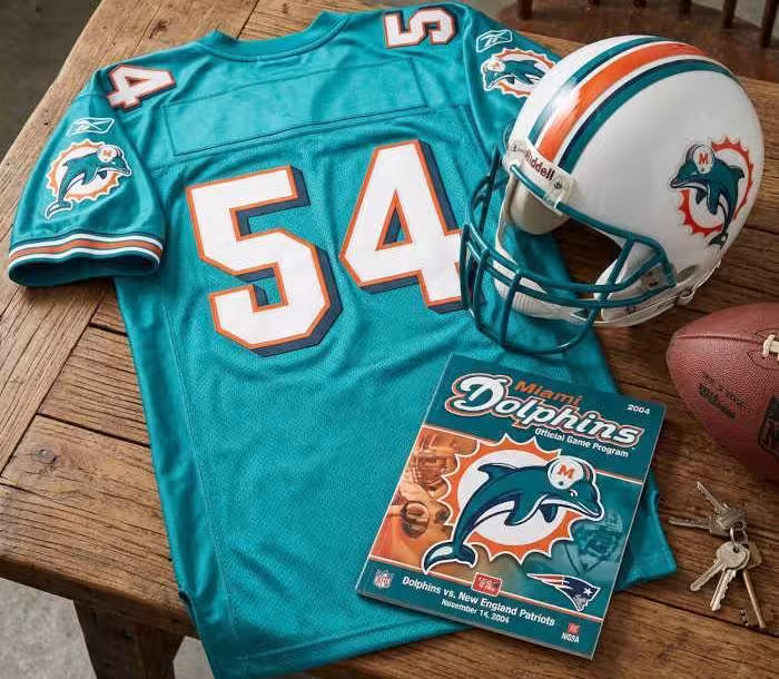 Gemini AI-created image of a 2004-era Miami NFL American football jersey 54, without a name on it, and a matching period-correct helmet, the program cover appropriate to the era and team.