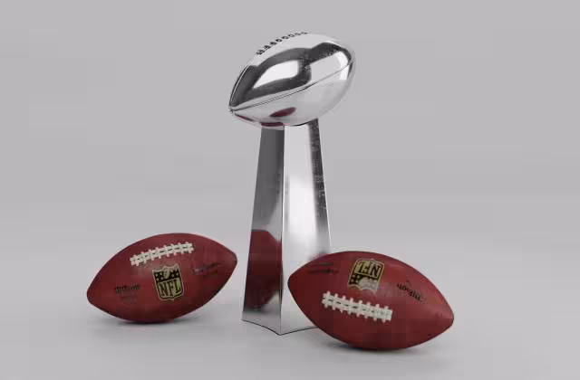 Full color Image of the Lombardi trophy with two NFL Wilson footballs sitting on either side of it.