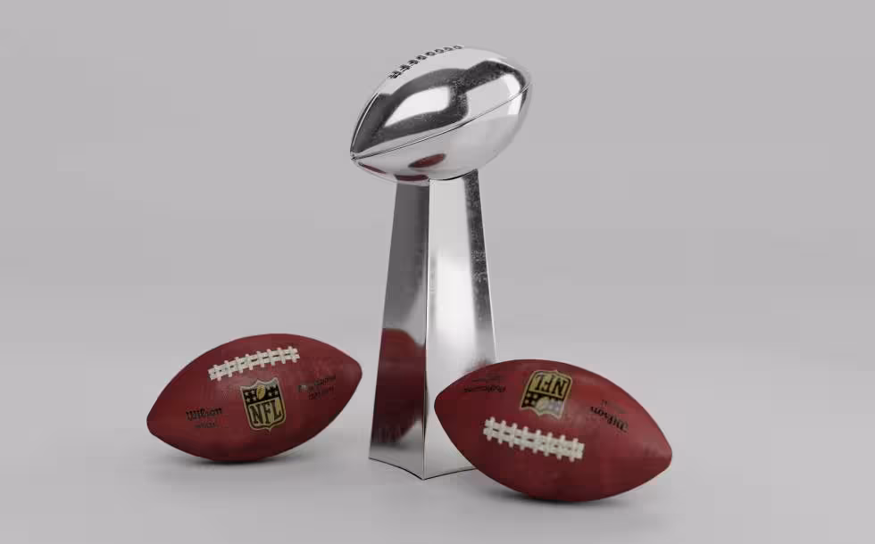 Full color Image of the Lombardi trophy with two NFL Wilson footballs sitting on either side of it.