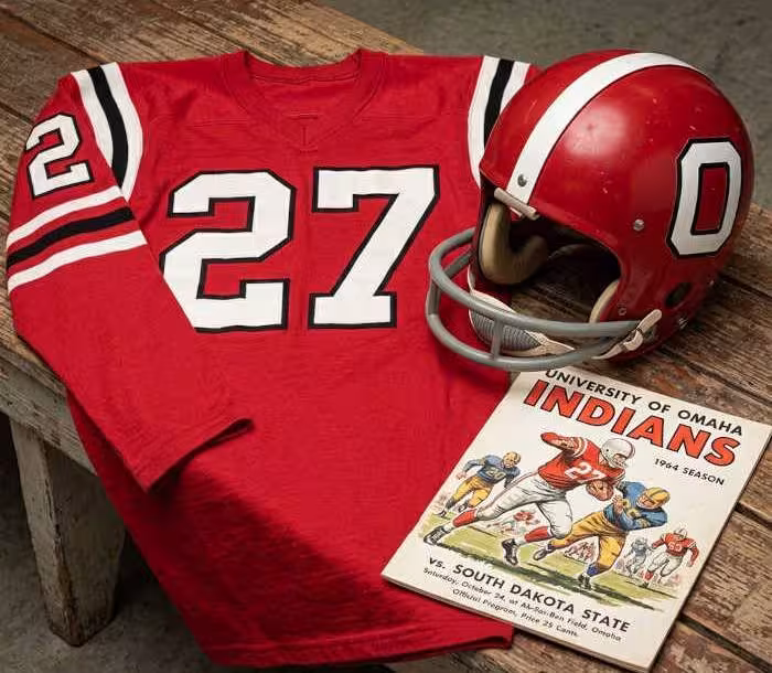 Gemini AI-created image of a 1964-era Nebraska Omaha American football jersey 27, without a name on it, and a matching period-correct helmet, the program cover appropriate to the era and team.