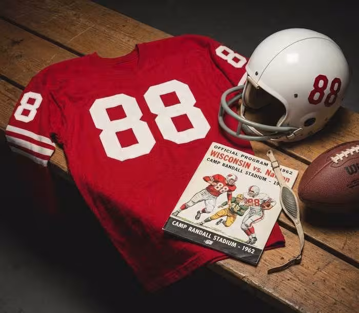 Gemini AI-created image of a 1962-era Wisconsin American football jersey 88, without a name on it, and a matching period-correct helmet, the program cover appropriate to the era and team.