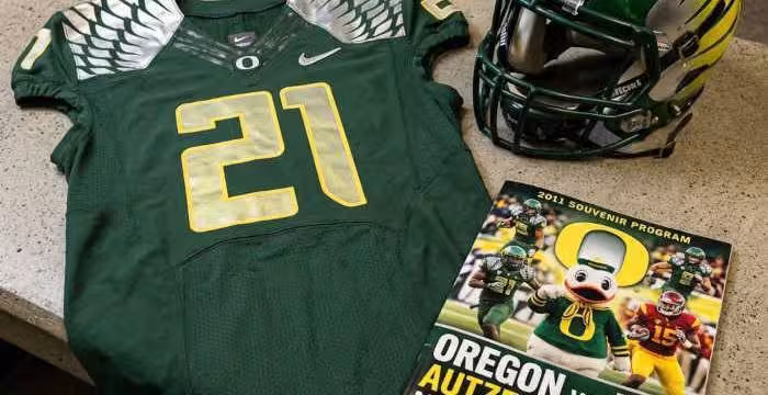 Gemini AI-created image of a 2011-era University of Oregon American football jersey 21 jersey, without a name on it, and a matching period-correct helmet, the program cover appropriate to the era and team.