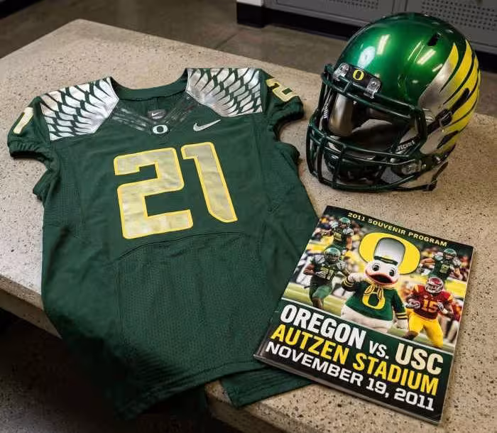 Gemini AI-created image of a 2011-era University of Oregon American football jersey 21 jersey, without a name on it, and a matching period-correct helmet, the program cover appropriate to the era and team.