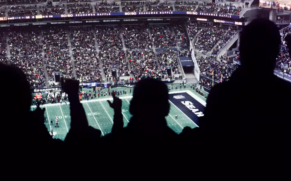 Image of a crowd of people watching a football game. By Caleb Woods via Unsplash..com